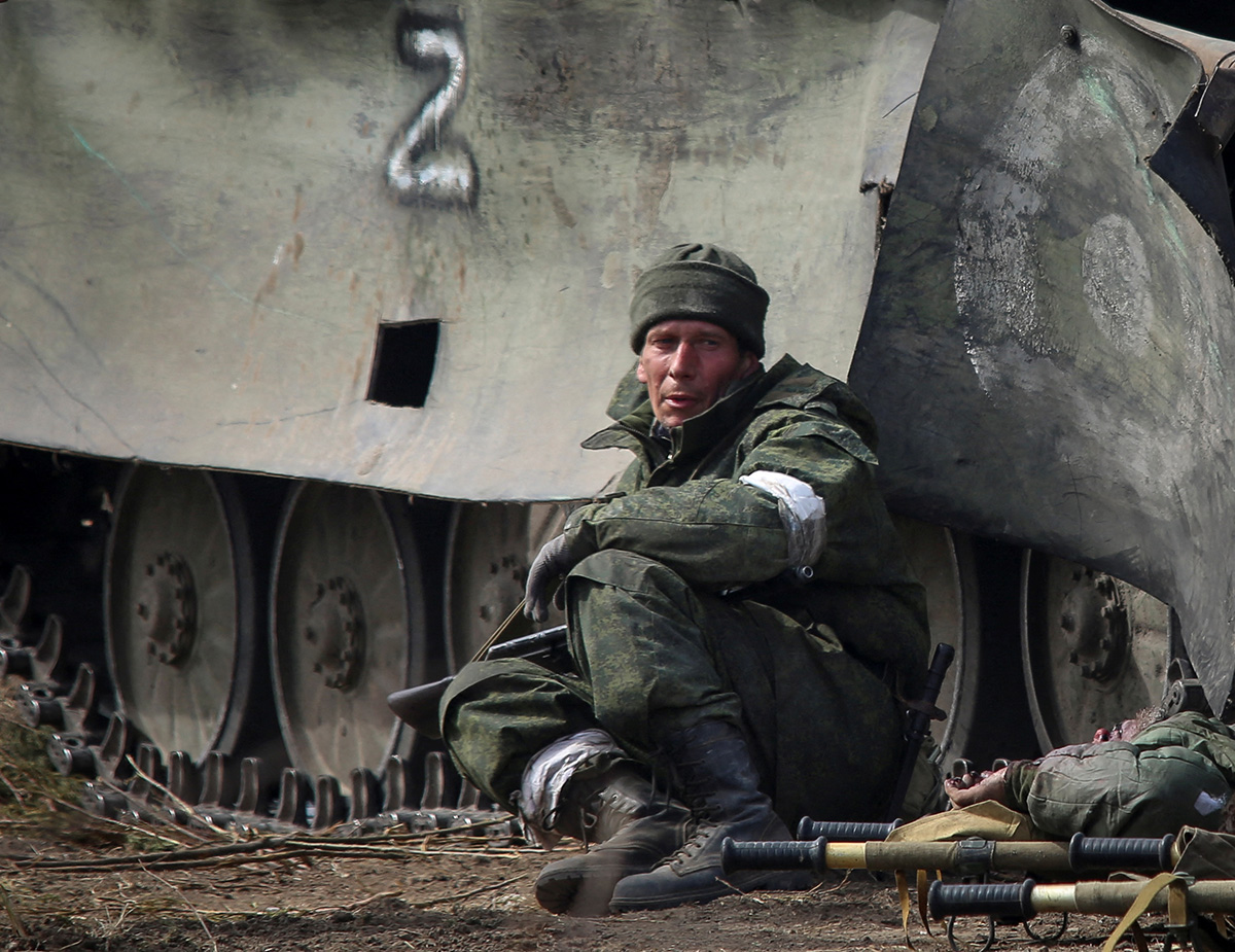 SENSITIVE MATERIAL. THIS IMAGE MAY OFFEND OR DISTURB    A service member of pro-Russian troops sits next to a body of a serviceman killed in fighting in Ukraine-Russia conflict in the city of Mariupol, Ukraine March 31, 2022.  REUTERS/Chingis Kondarov  NO RESALES. NO ARCHIVES.